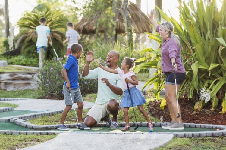 Interracial family, two children playing miniature golf