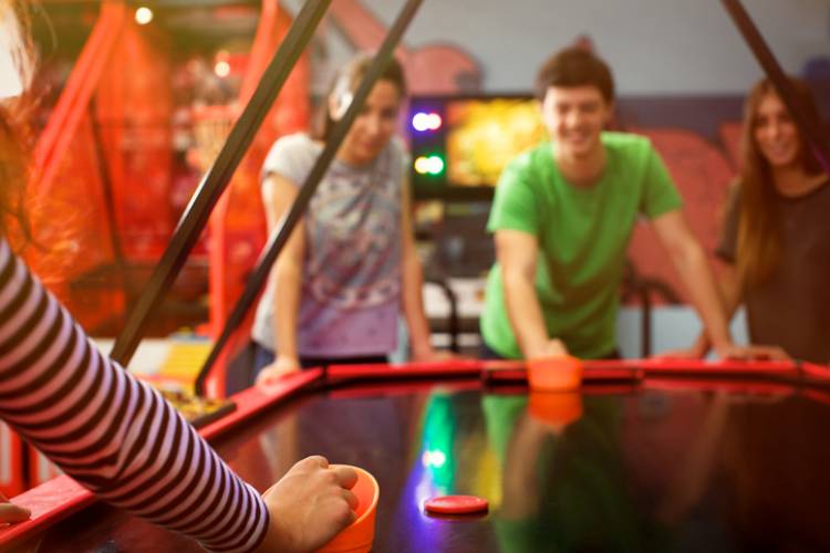 four friends having fun and playing air hockey game