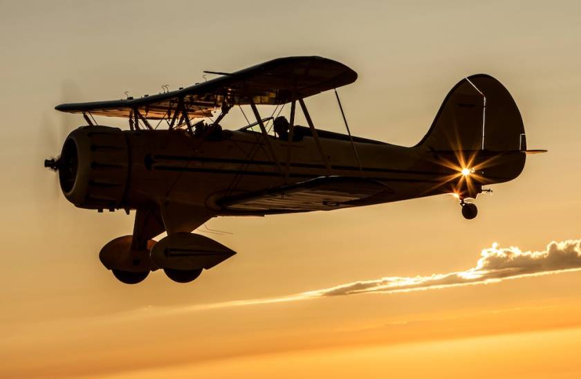 biplane flying in sunset sky